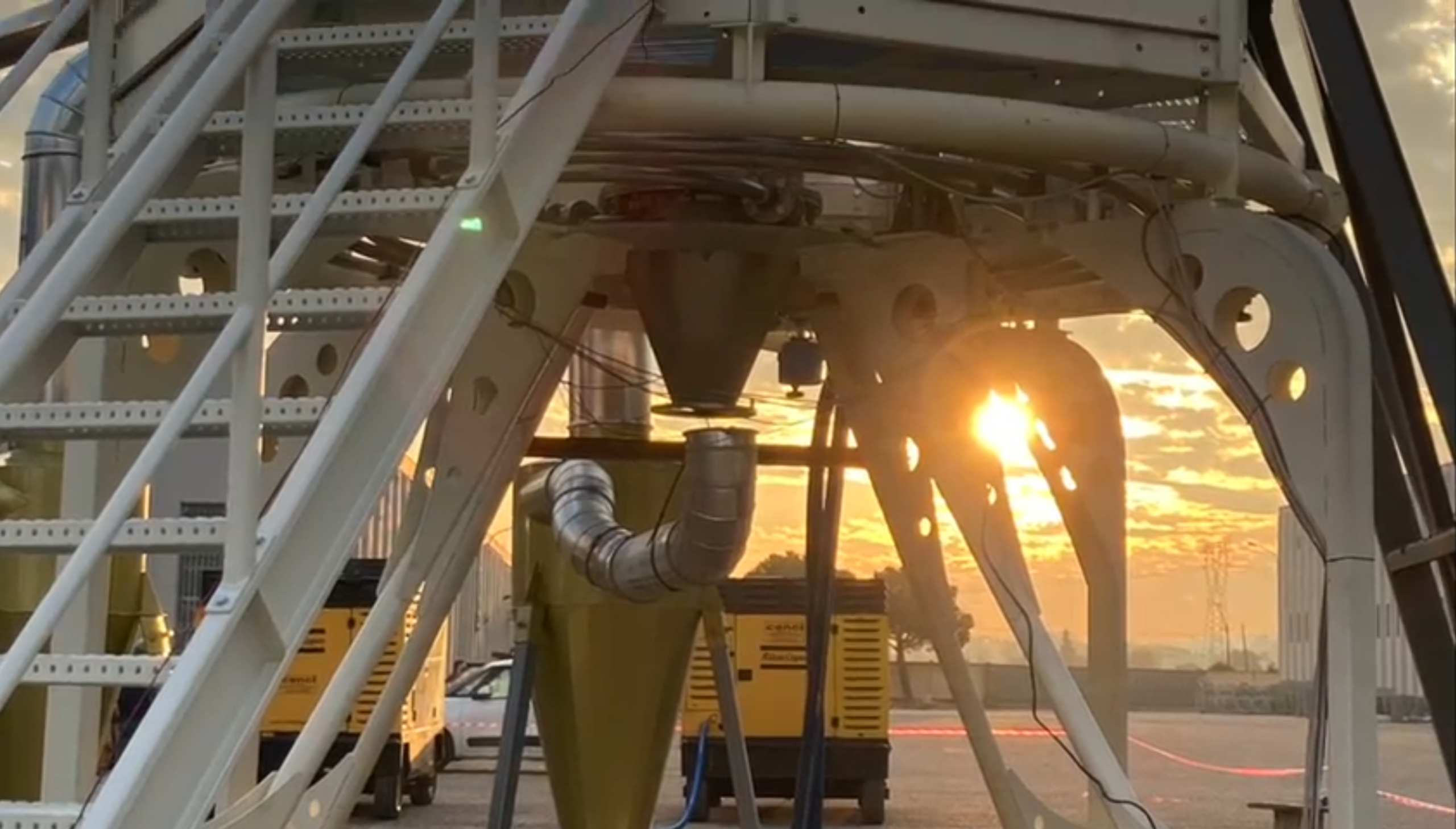 Una bobina di Tesla emette scariche elettriche in un ambiente industriale notturno sotto un cielo tempestoso.